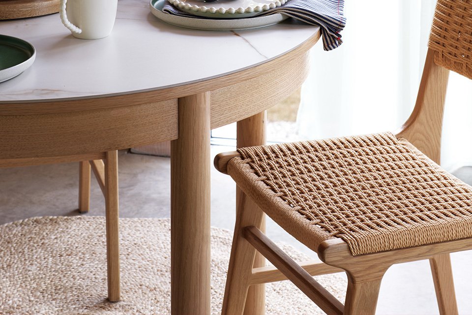 A beige circular rug under a round wooden table.